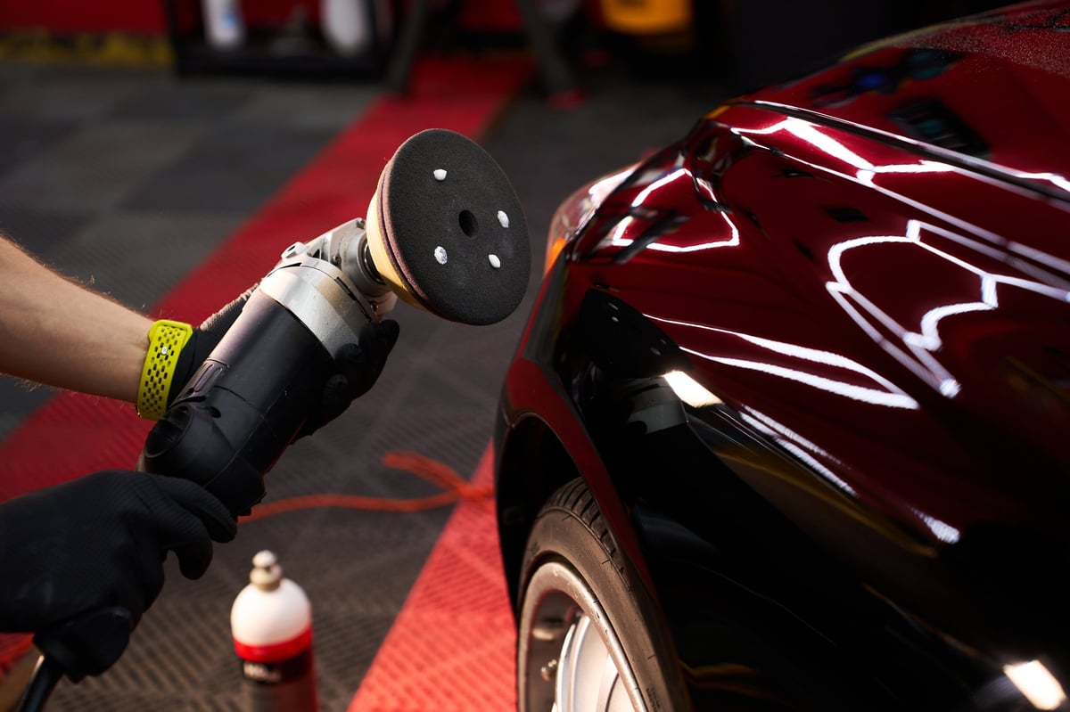 Detailer polishing a car to restore a deep factory gloss finish